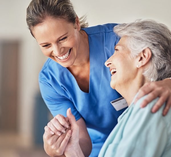 Shot of a young caregiver caring for her elderly patient in her home