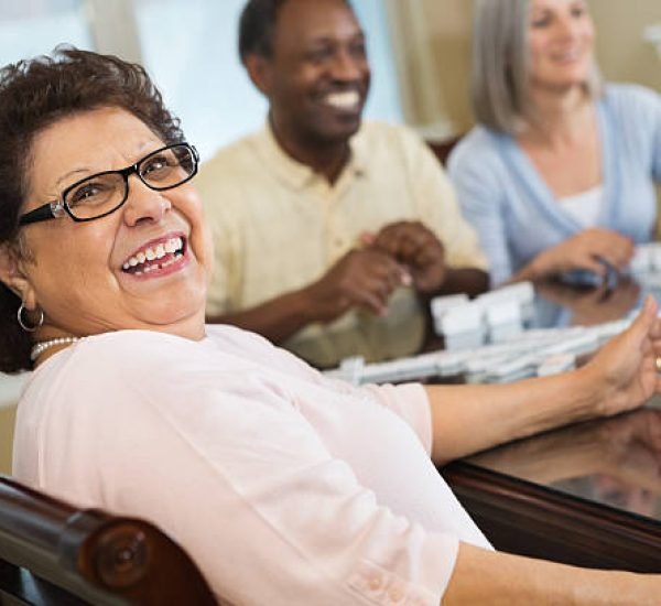 Happy Hispanic senior woman playing dominoes with friends