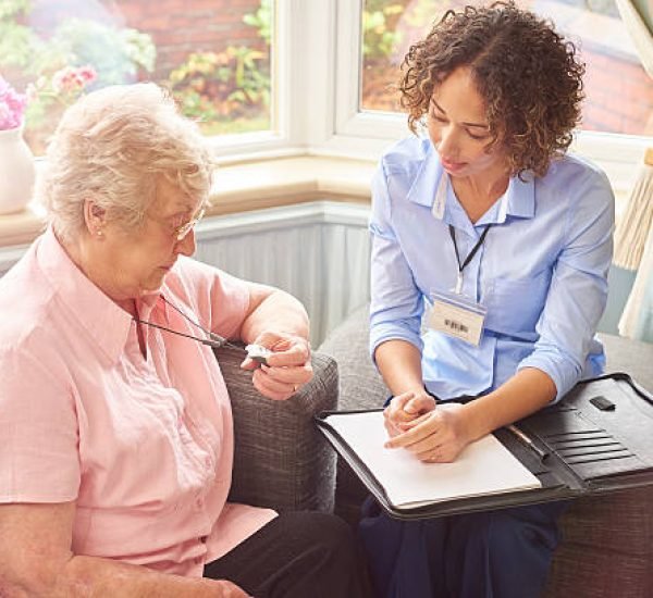 a housing official or sheltered scheme manager demonstrates to a senior woman how her panic pendant would work in the event of a fall .